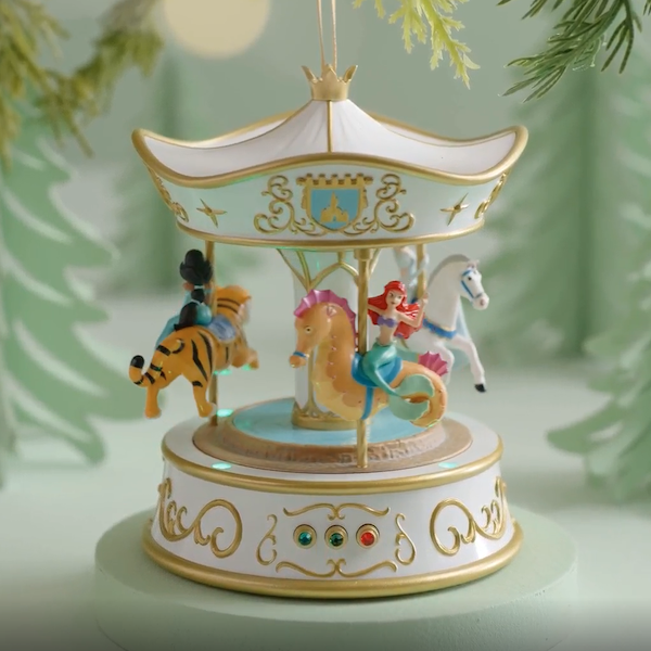 A Keepsake Ornament featuring Disney Princesses Ariel, Jasmine and Cinderella on a gold and white carousel.